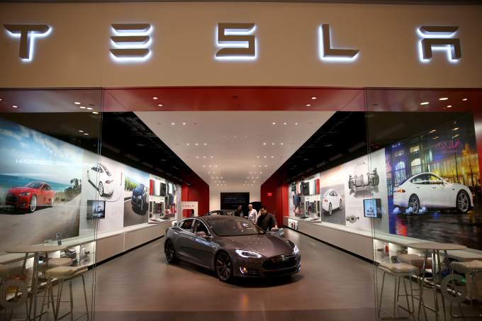 MIAMI, FL - FEBRUARY 19:  People look at a Tesla Motors vehicle on the showroom floor at the Dadeland Mall on February 19, 2014 in Miami, Florida.  Tesla said today it earned $ 46 million in the fourth quarter on a non-adjusted basis, or 33 cents a share, causing shares in the company to jump 12 percent.  (Photo by Joe Raedle/Getty Images)