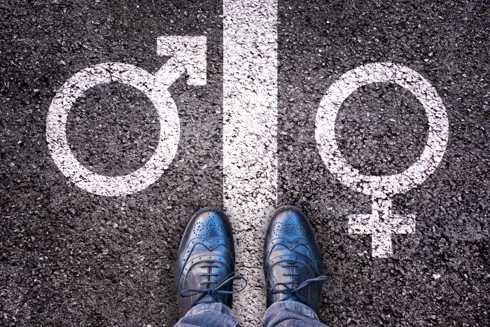 Person standing on a line between gender symbols.