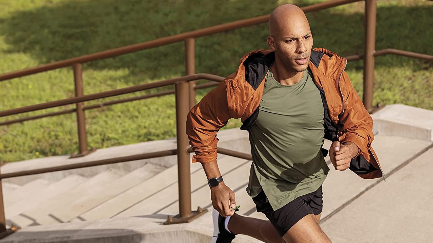 Man jogging wearing black fitbit on right arm