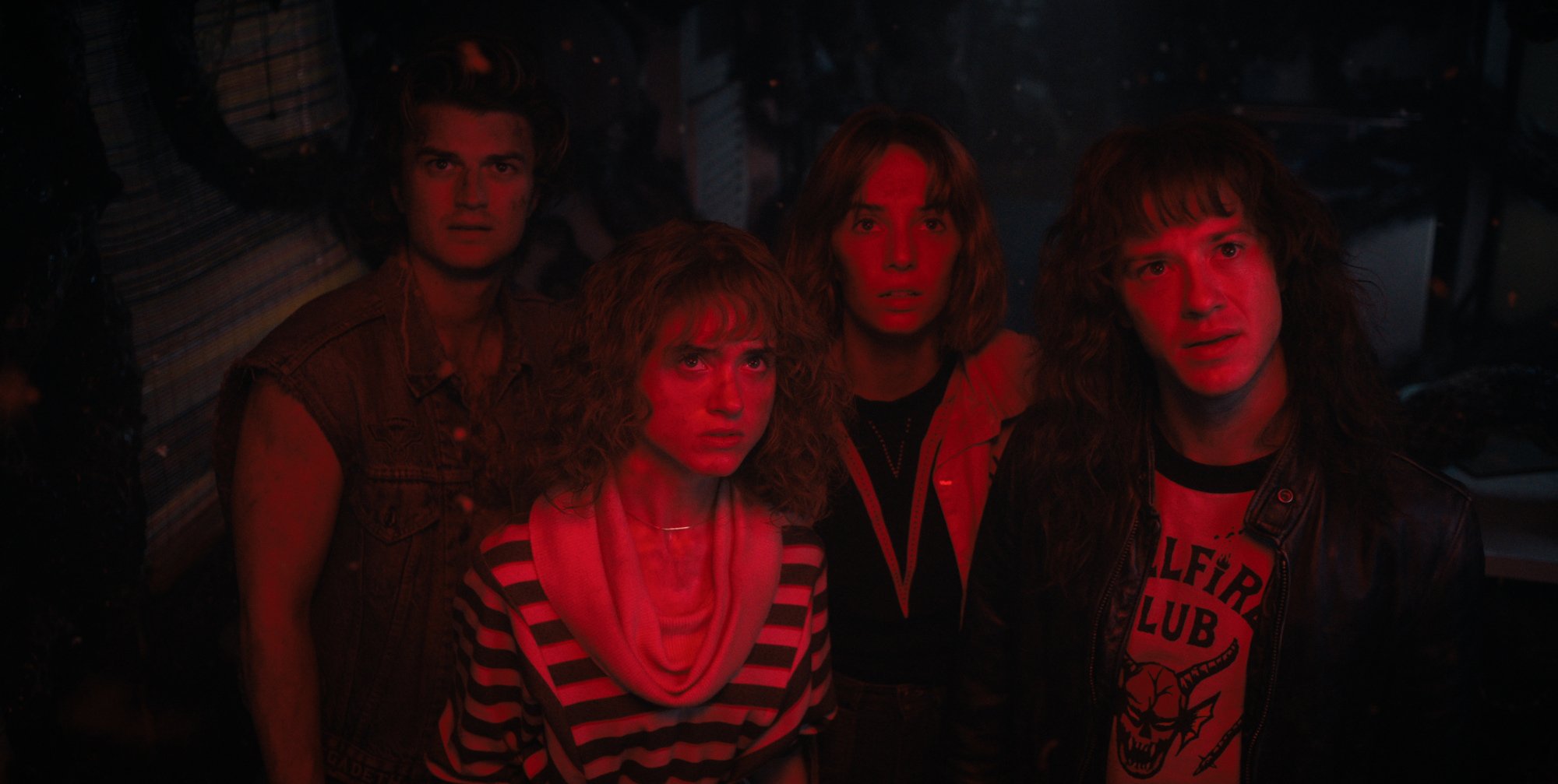 A group of four teenagers bathed in red light