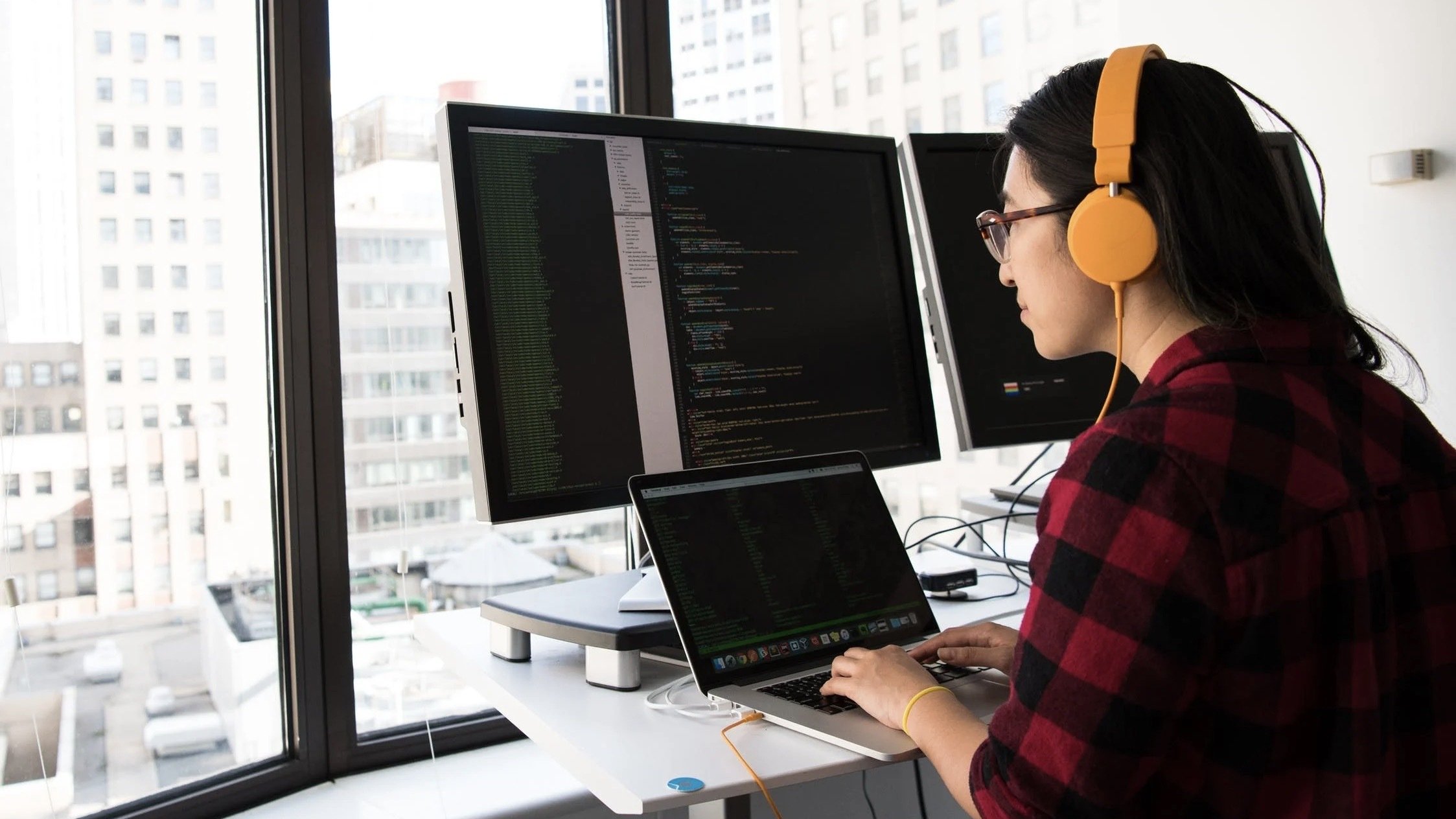 Person coding on their laptop and monitor.