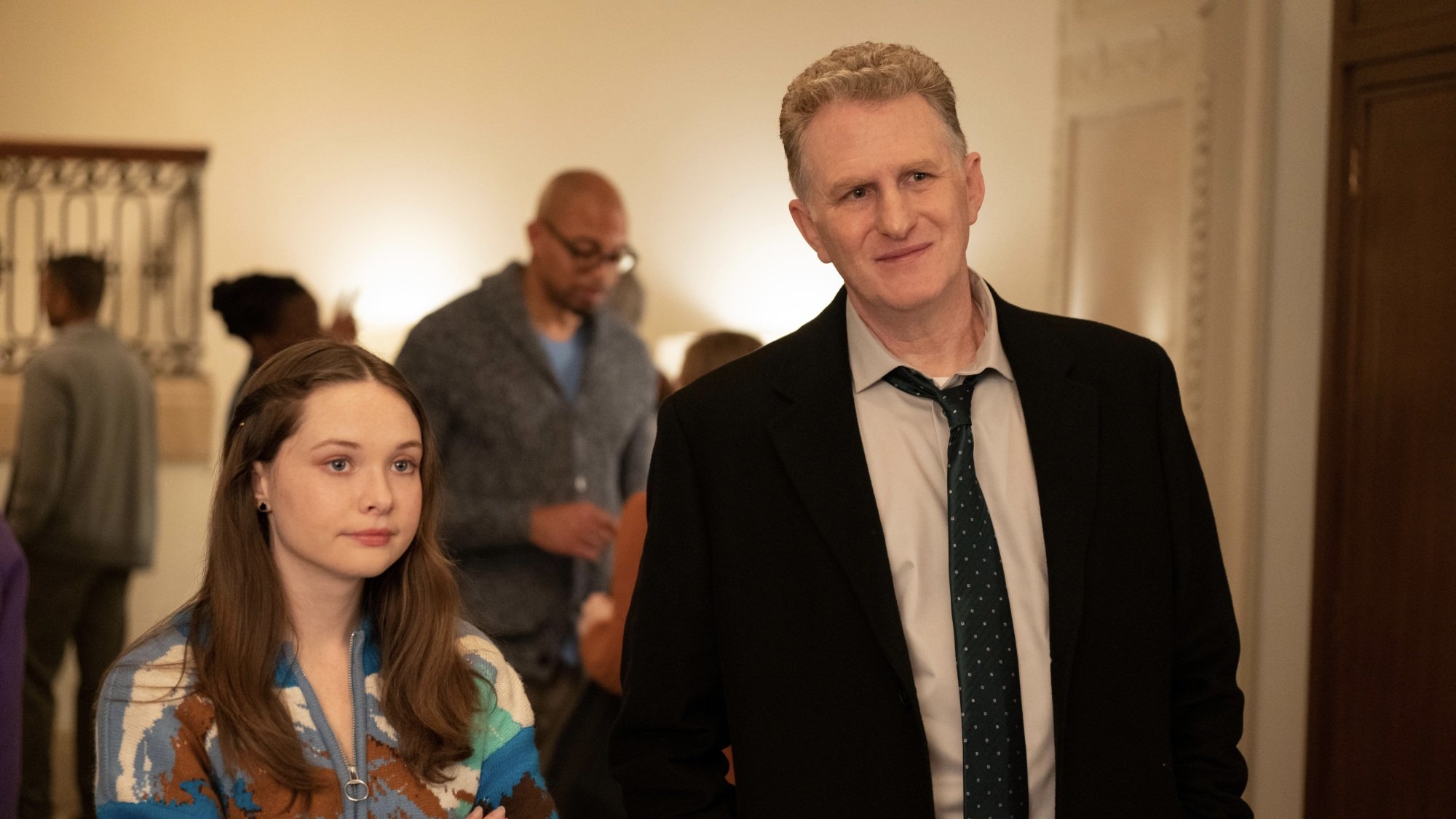 A young woman and a man stand side by side in an apartment building lobby.